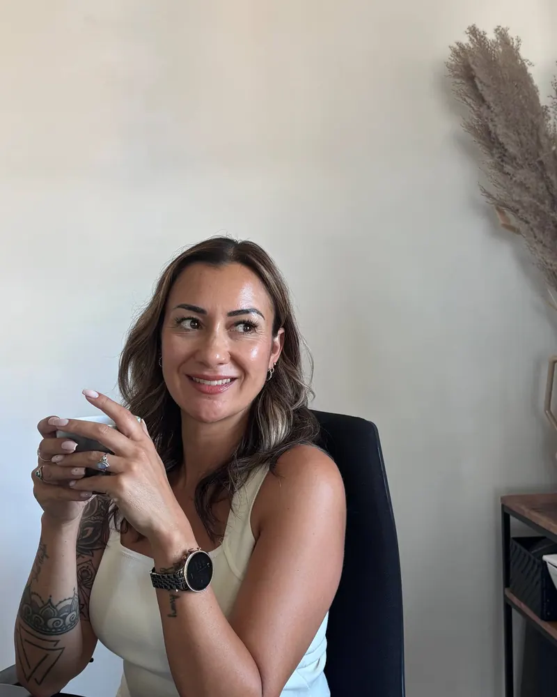 Jordana Ninkeula lacht ontspannen aan tafel met een kop koffie